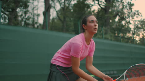 Revés-Del-Joven-Tenista.-Niña-Con-Camiseta-Rosa-Jugando-Tenis-Sobre-Césped-Al-Atardecer.-Altura-De-Los-Ojos